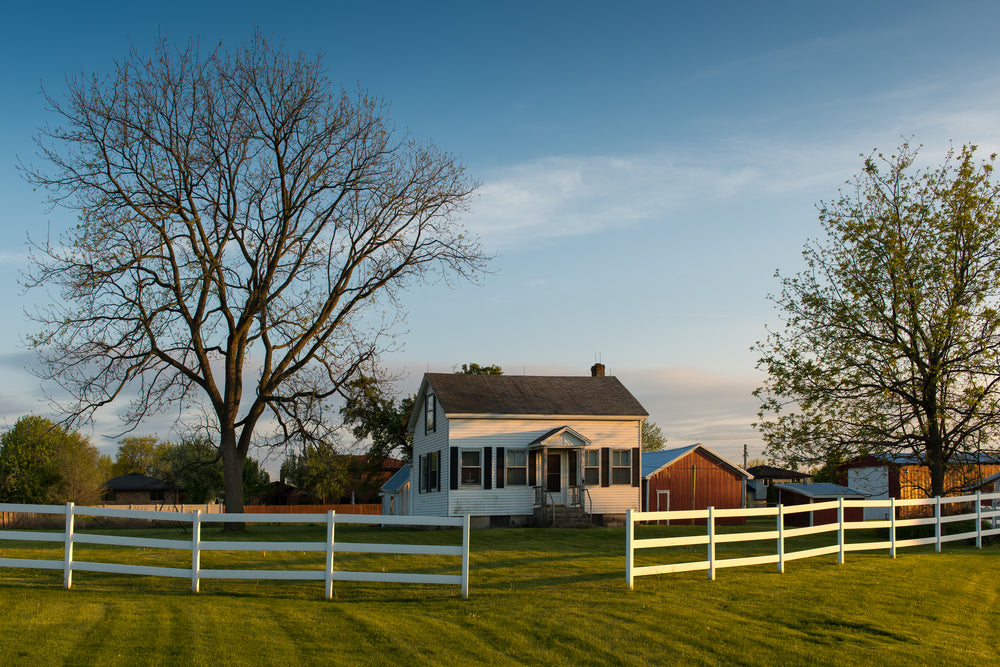 White farmhouse behind white fence 