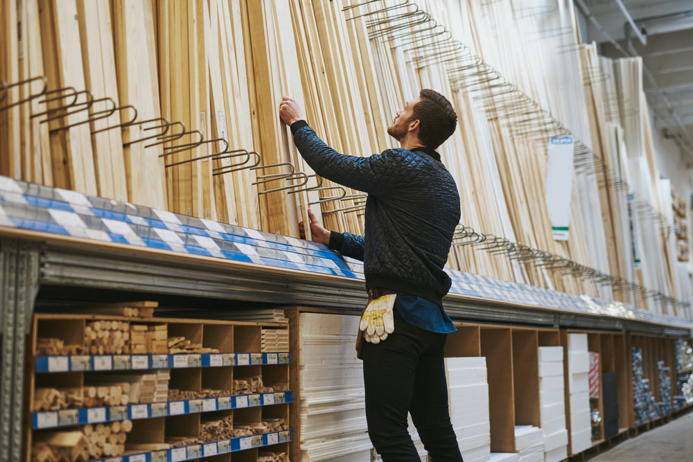Carpenter selecting lengths of cut wood of a rack in a hardware store