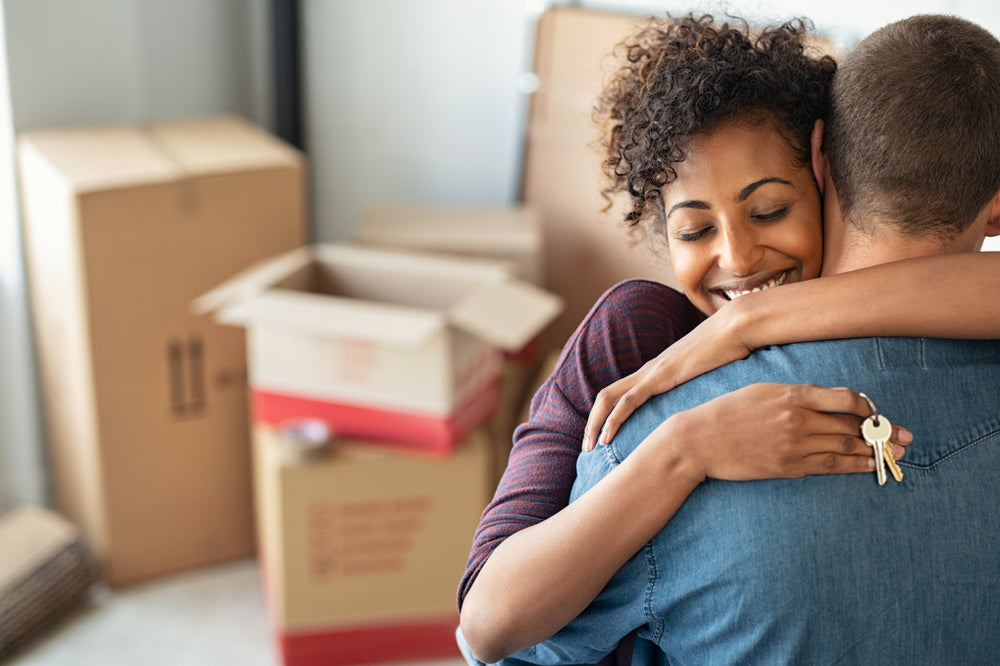Young african woman holding home keys while hugging boyfriend 